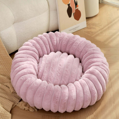 Plush pet bed for winter in soft pink color, featuring a cozy and comfortable round design for pets.